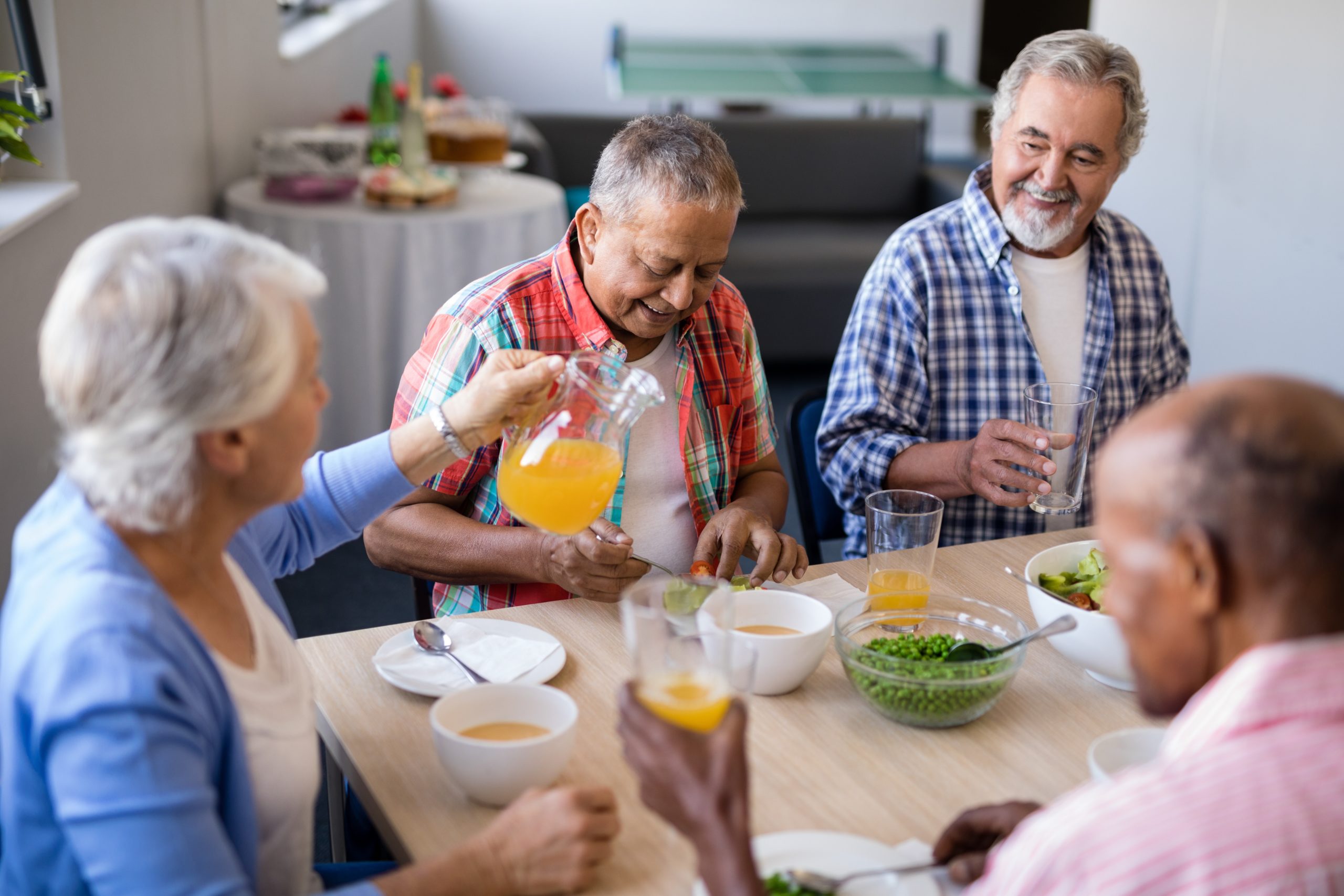 Senior female serving drink to male friends