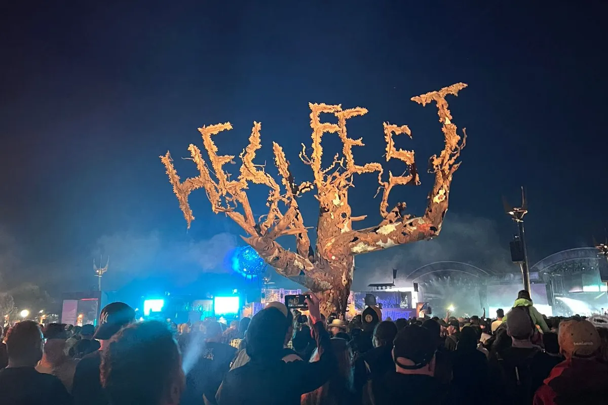 Ambiance nocturne au Hellfest avec la sculpture emblématique entourée du public