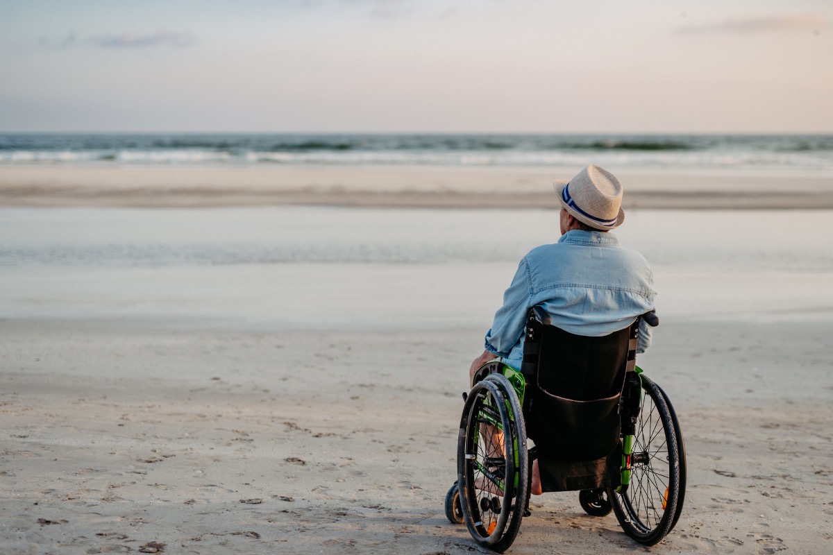 Personne accompagnée lors d’une sortie estivale, illustrant l’accessibilité de la plage pour les personnes en situation de handicap