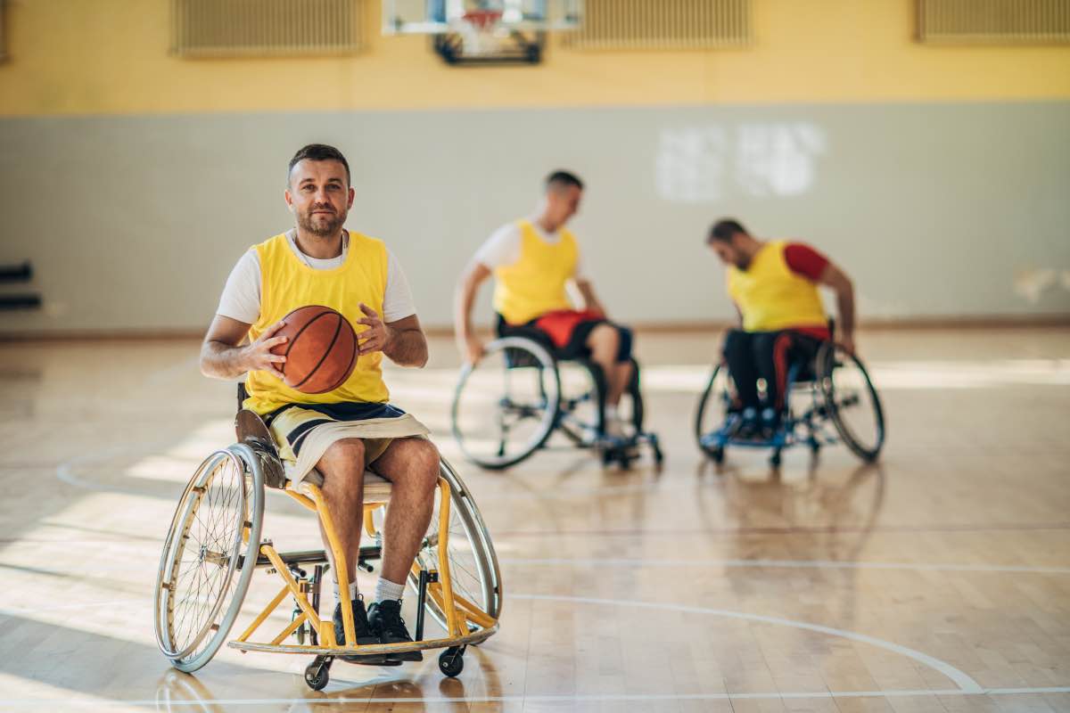 athlète handisport en fauteuil roulant tenant un ballon de basket dans ses mains