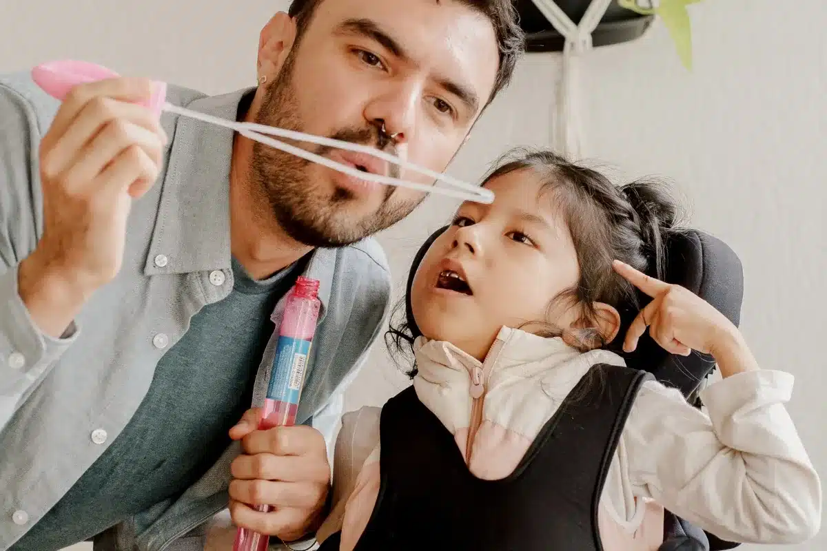 Intervenant professionnel jouant avec une enfant en situation de handicap, illustration de l'accompagnement spécialisé et de l'inclusion