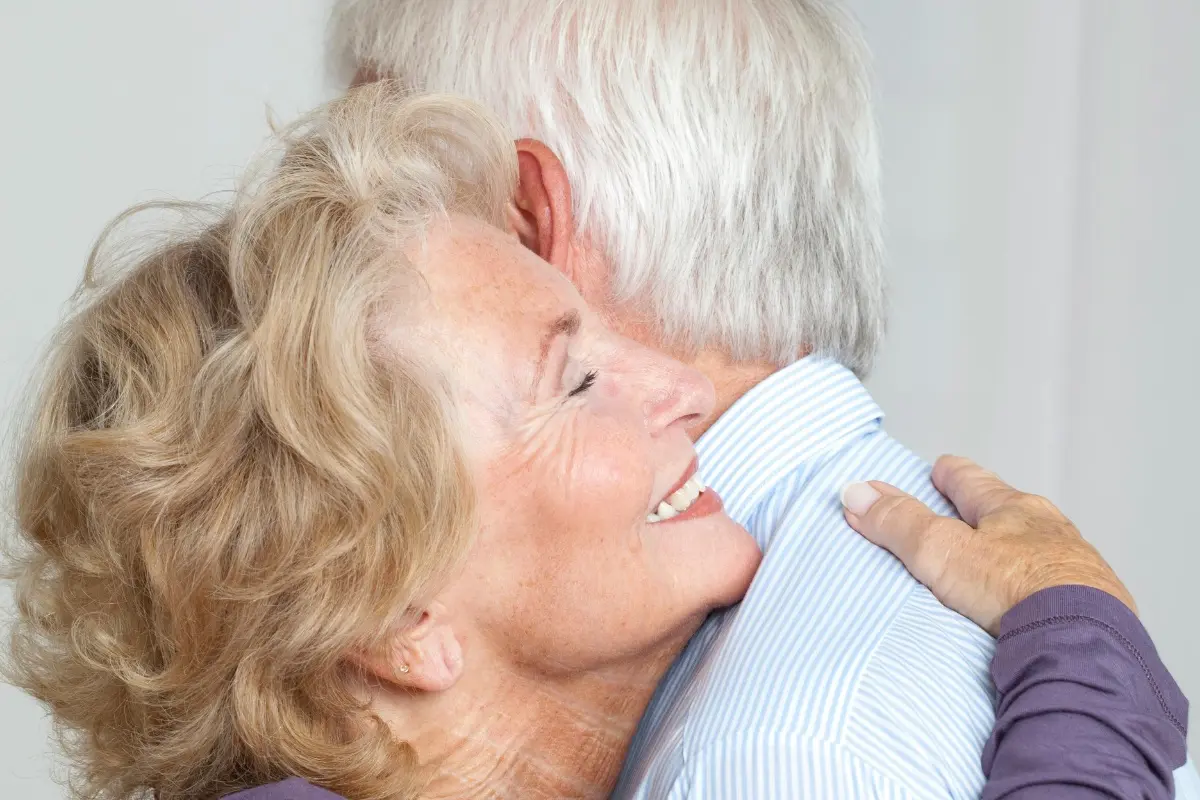 Couple de personnes âgées s'étreignant avec tendresse, illustrant la sérénité et le soutien apporté à un proche pendant les vacances de l'aidant